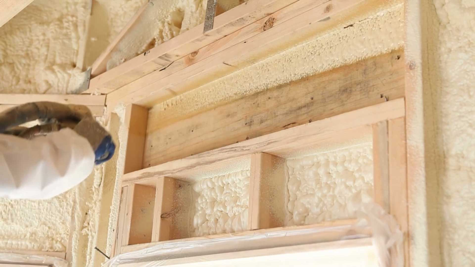 Fresh spray foam filling wall cavities around a window