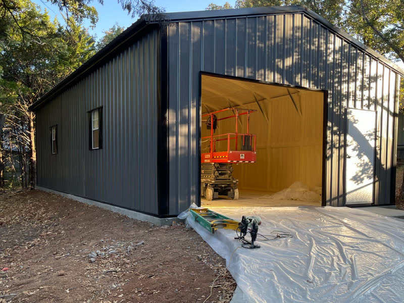 Metal building with the overhead door open, showing fresh spray foam insulation inside